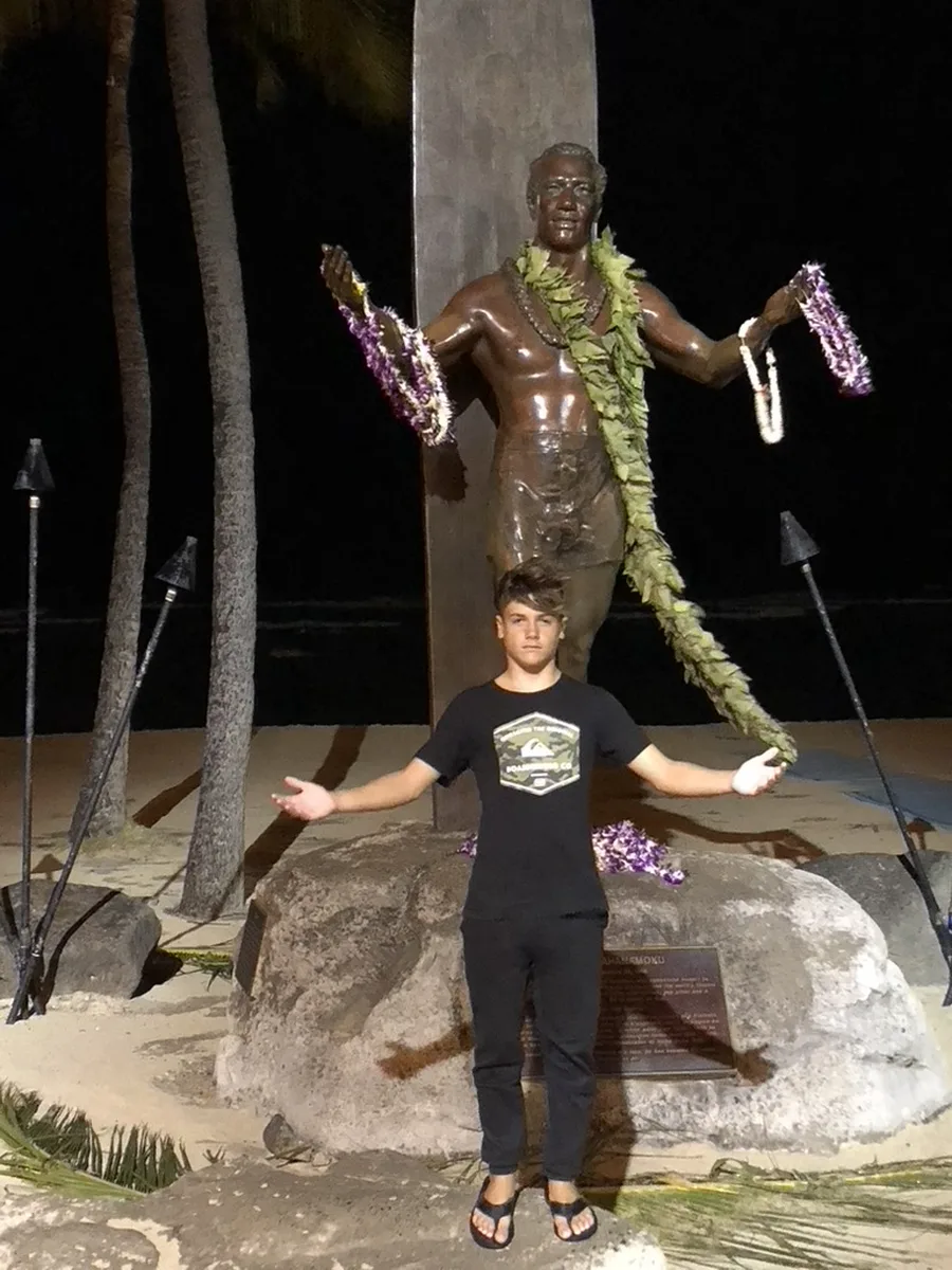 Kolby giving a shaka at the Duke Kahanamoku statue in Hawaii