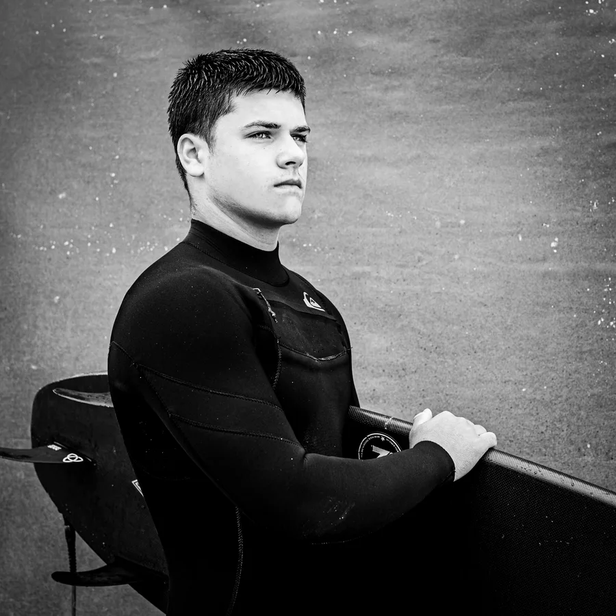Portrait of Kolby holding his surfboard